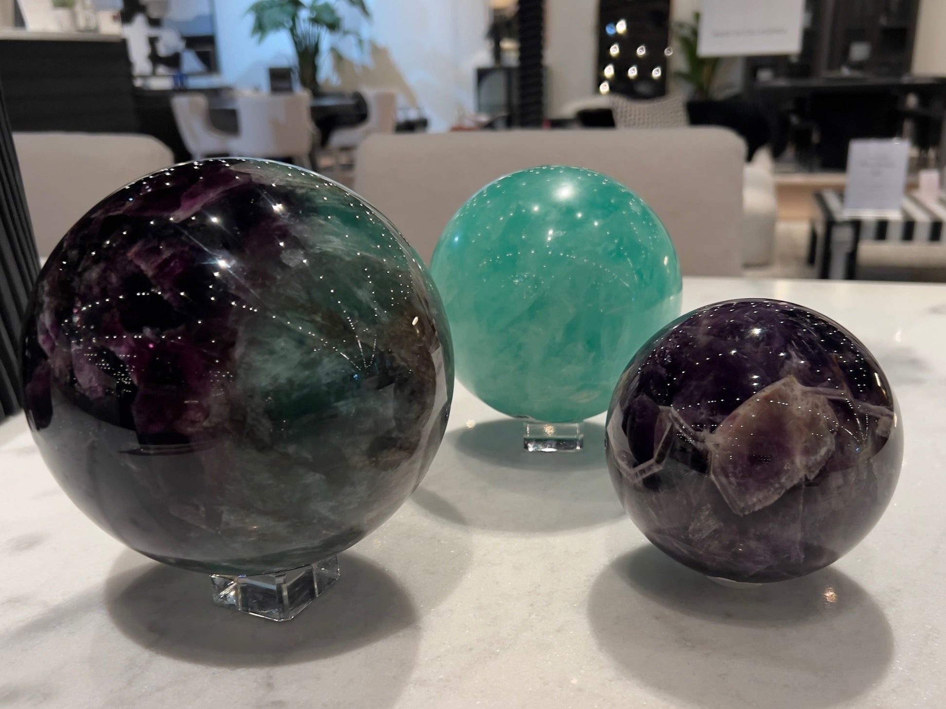 Three crystal spheres on a marble surface with a blurred indoor background