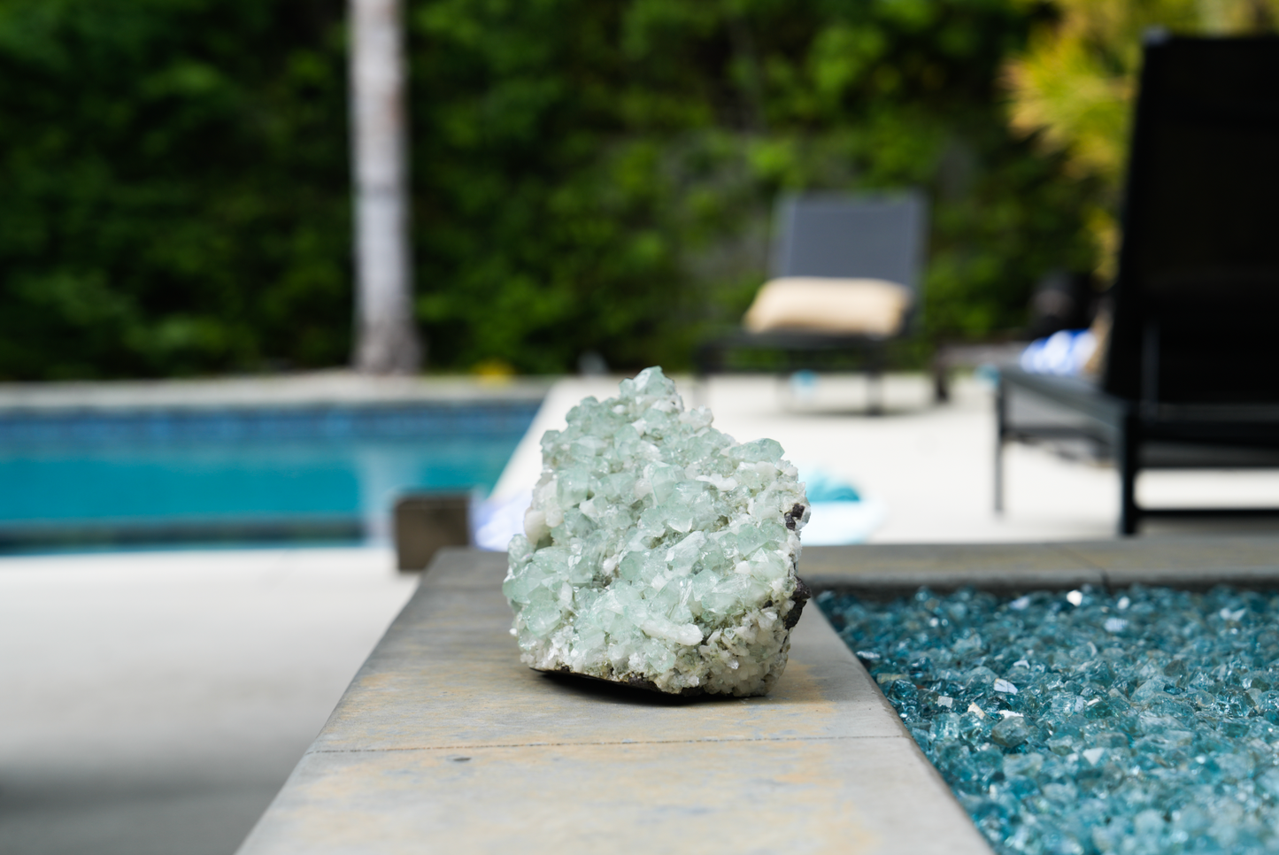 green apophyllite cluster with blurred pool and outdoor scene behind
