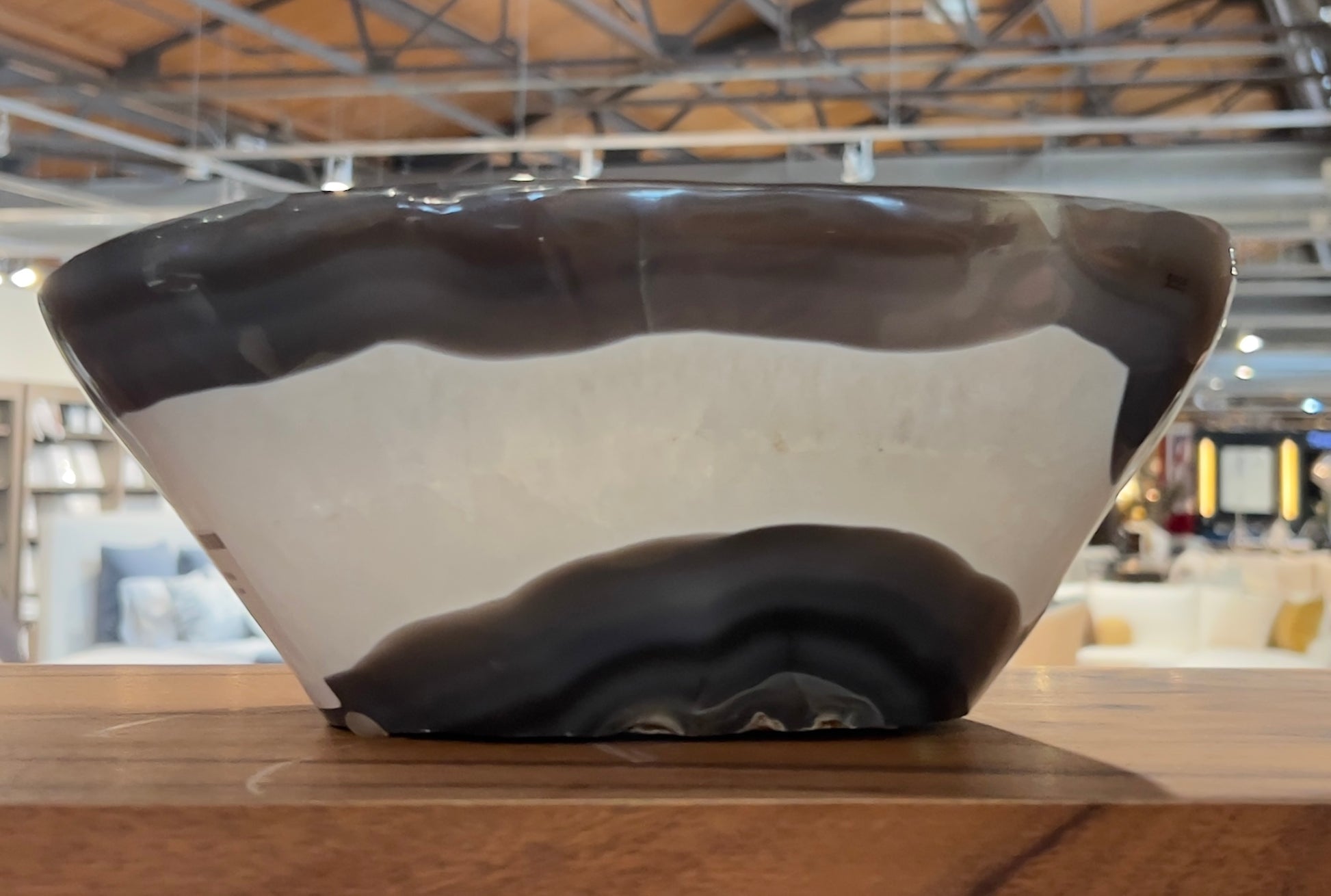 Close-up of sculptural grey and white agate quartz bowl with bold banding, displayed in a modern showroom.