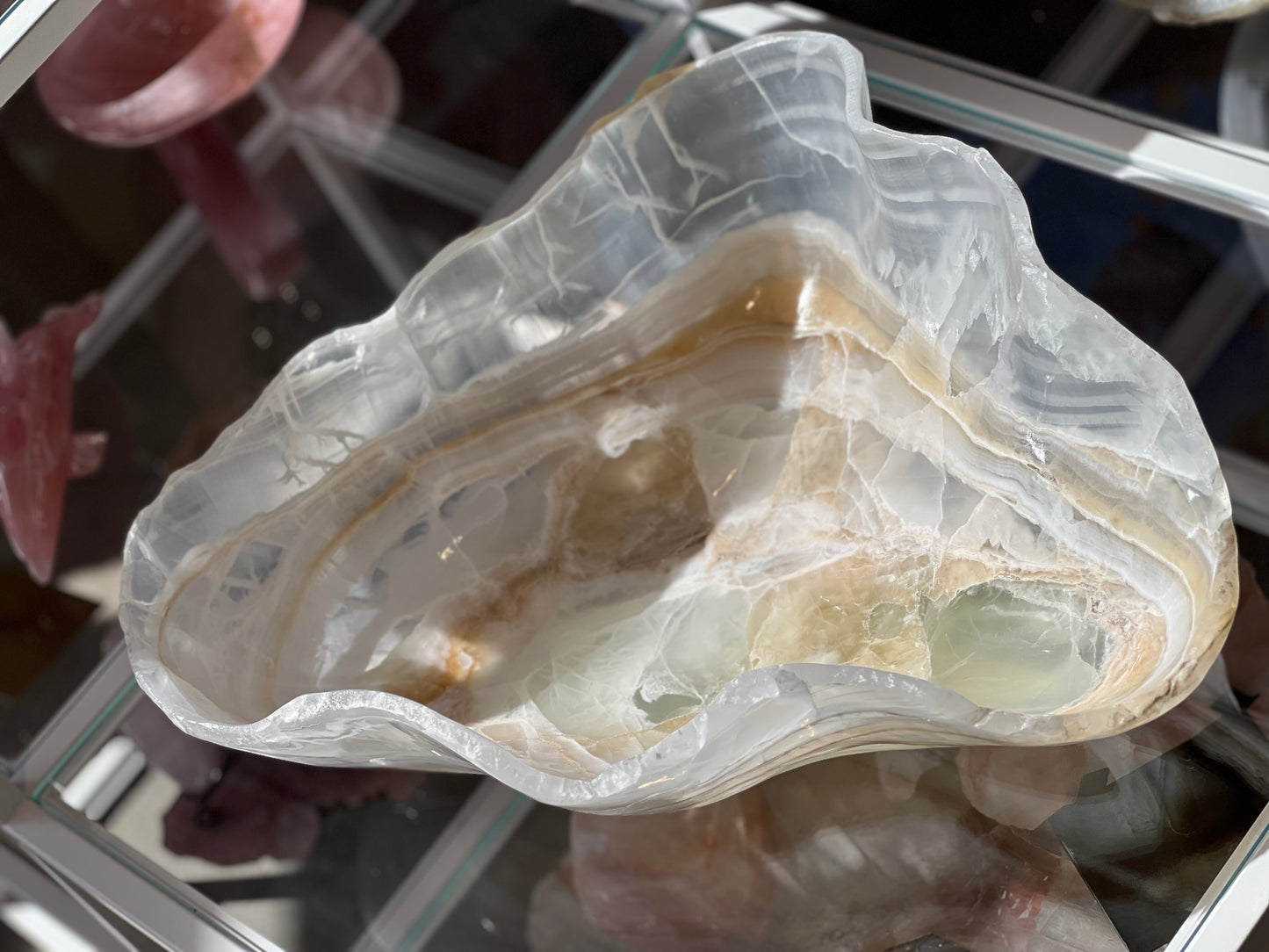 A hand-carved decorative bowl made of white and green onyx, displaying natural crystal patterns and a band of light brown