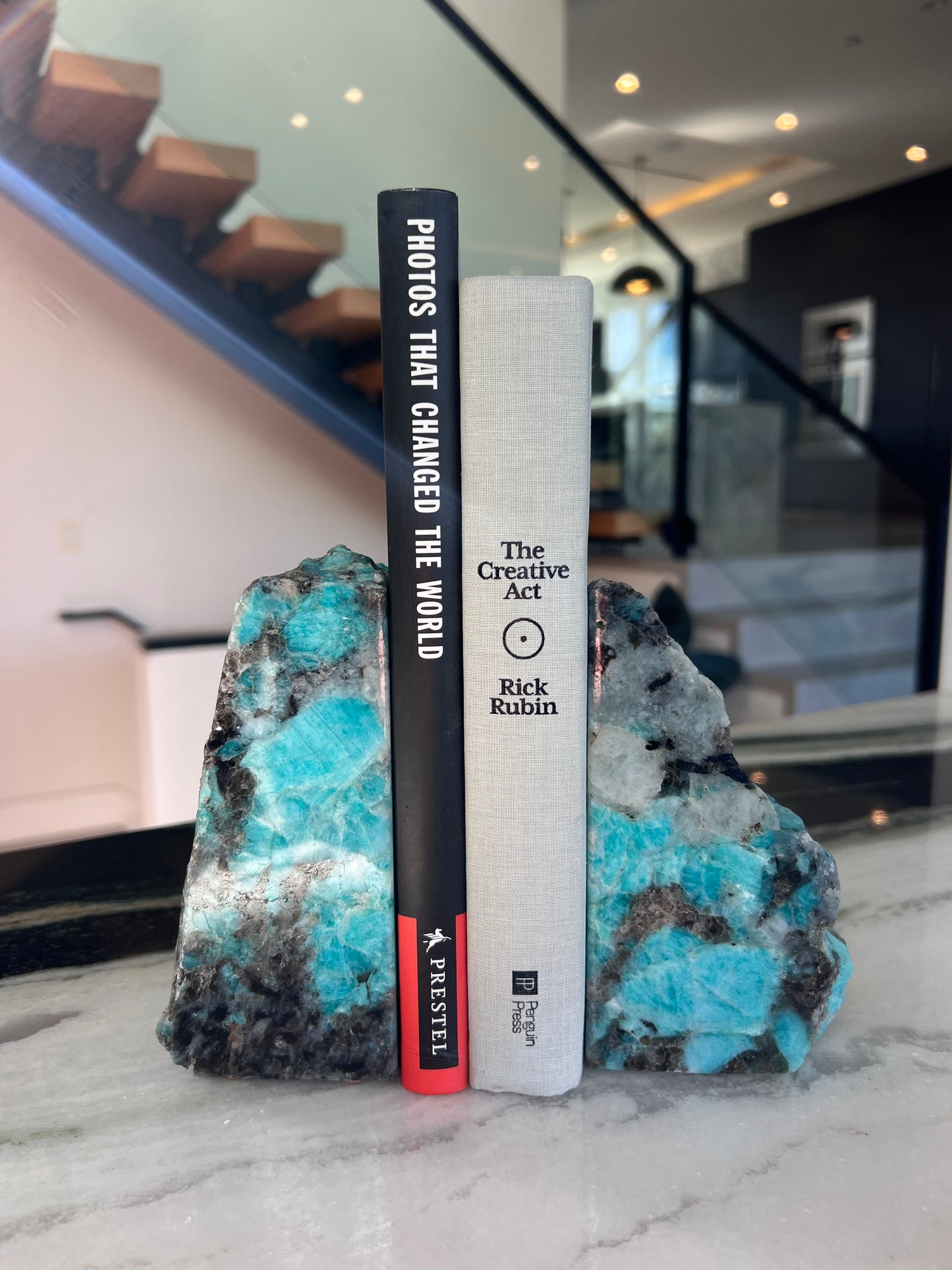 Books on a decorative stone surface held by amazonite bookends with a blurred indoor background.