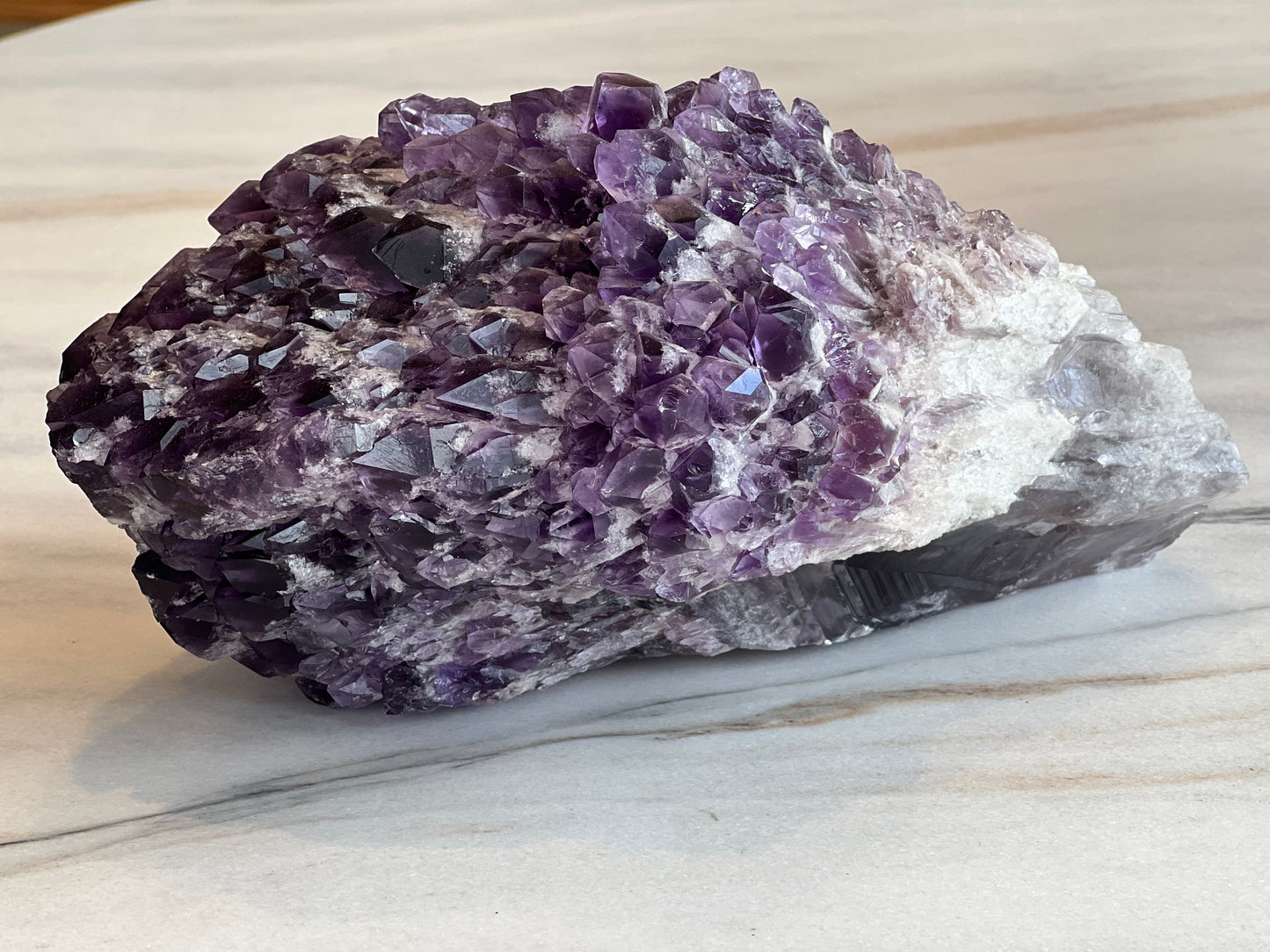 close up of amethyst cluster on marble table top