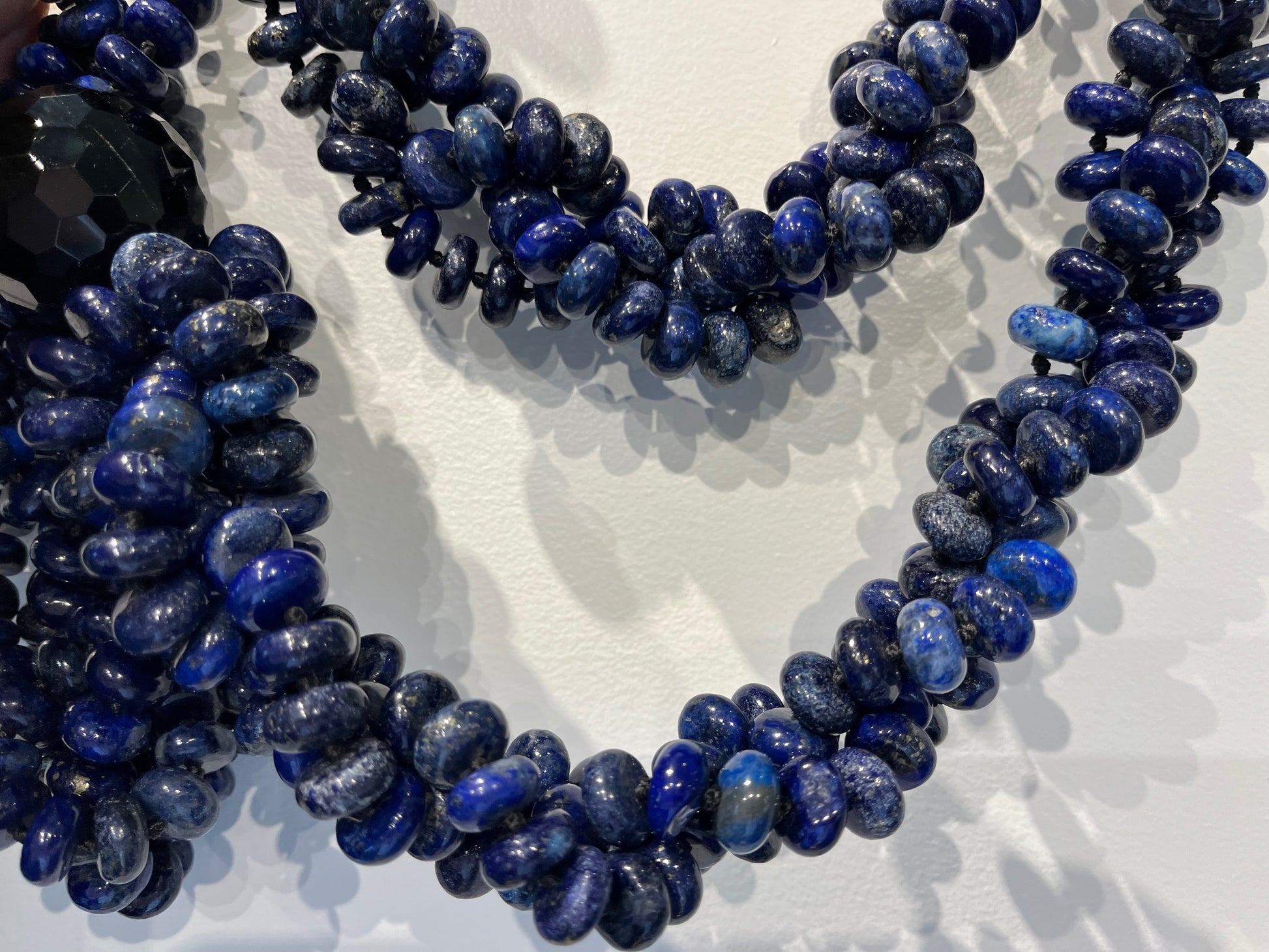 Close-up of richly textured lapis lazuli beads showing the deep blue and gold flecks in the hand-knotted mala necklace.