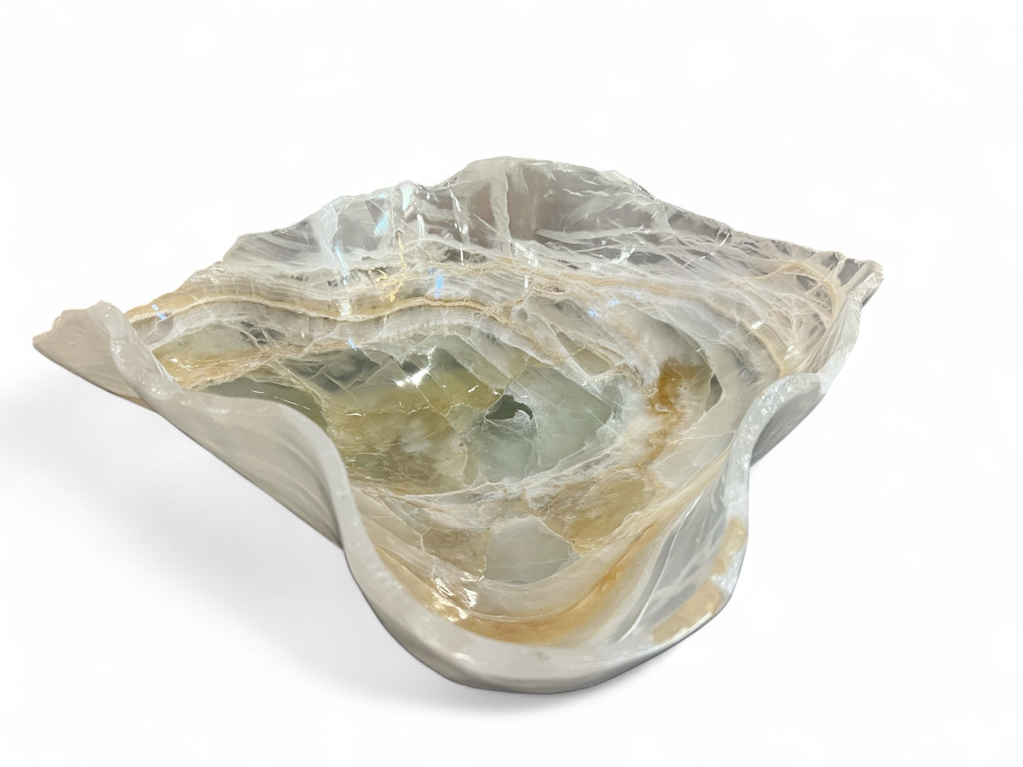 A polished carved white onyx bowl with light brown and green patterns.