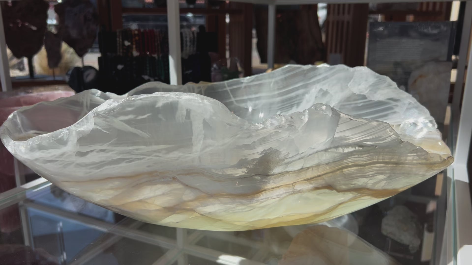 video of large hand carved white and green onyx bowl on glass shelf
