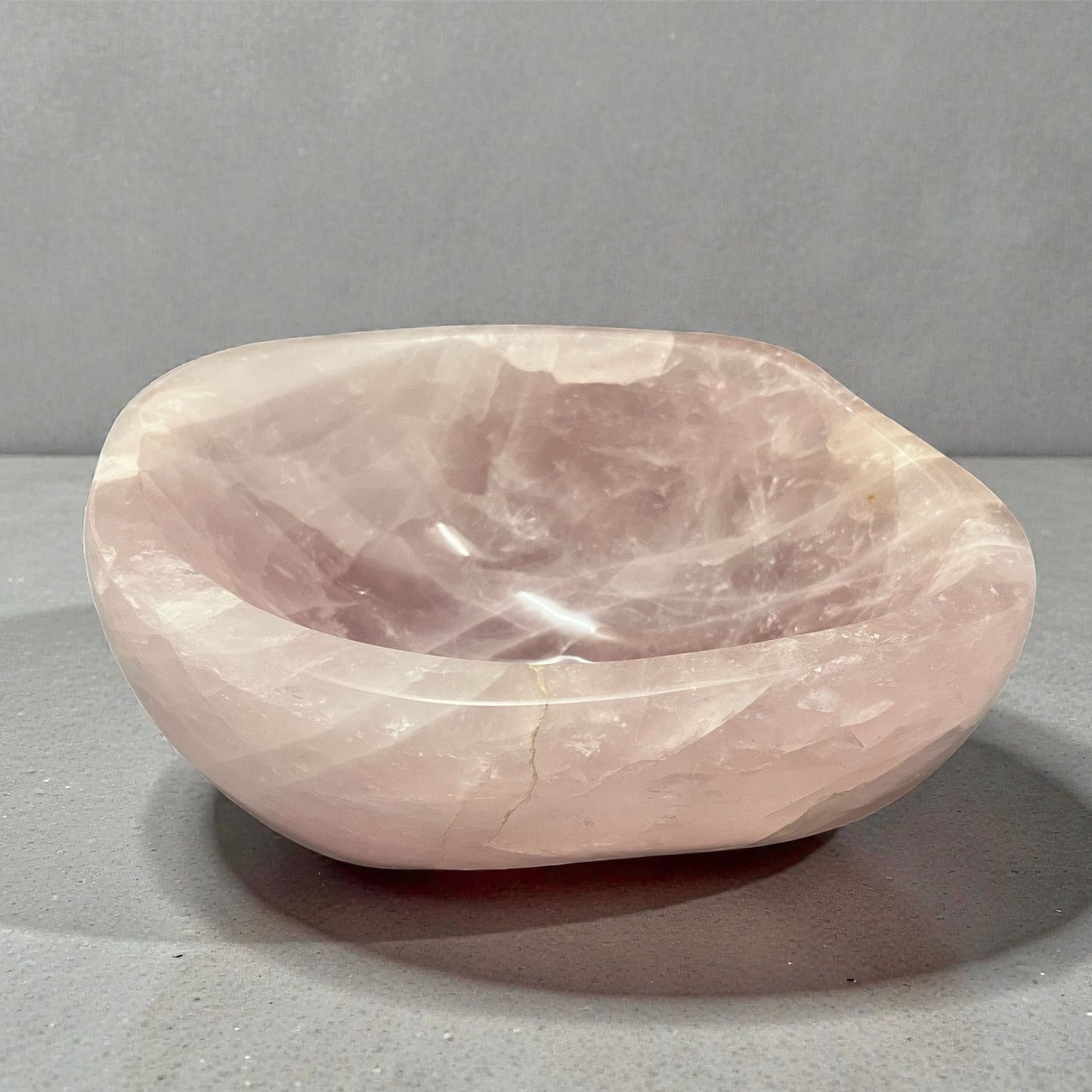 Rose quartz stone bowl on a gray background