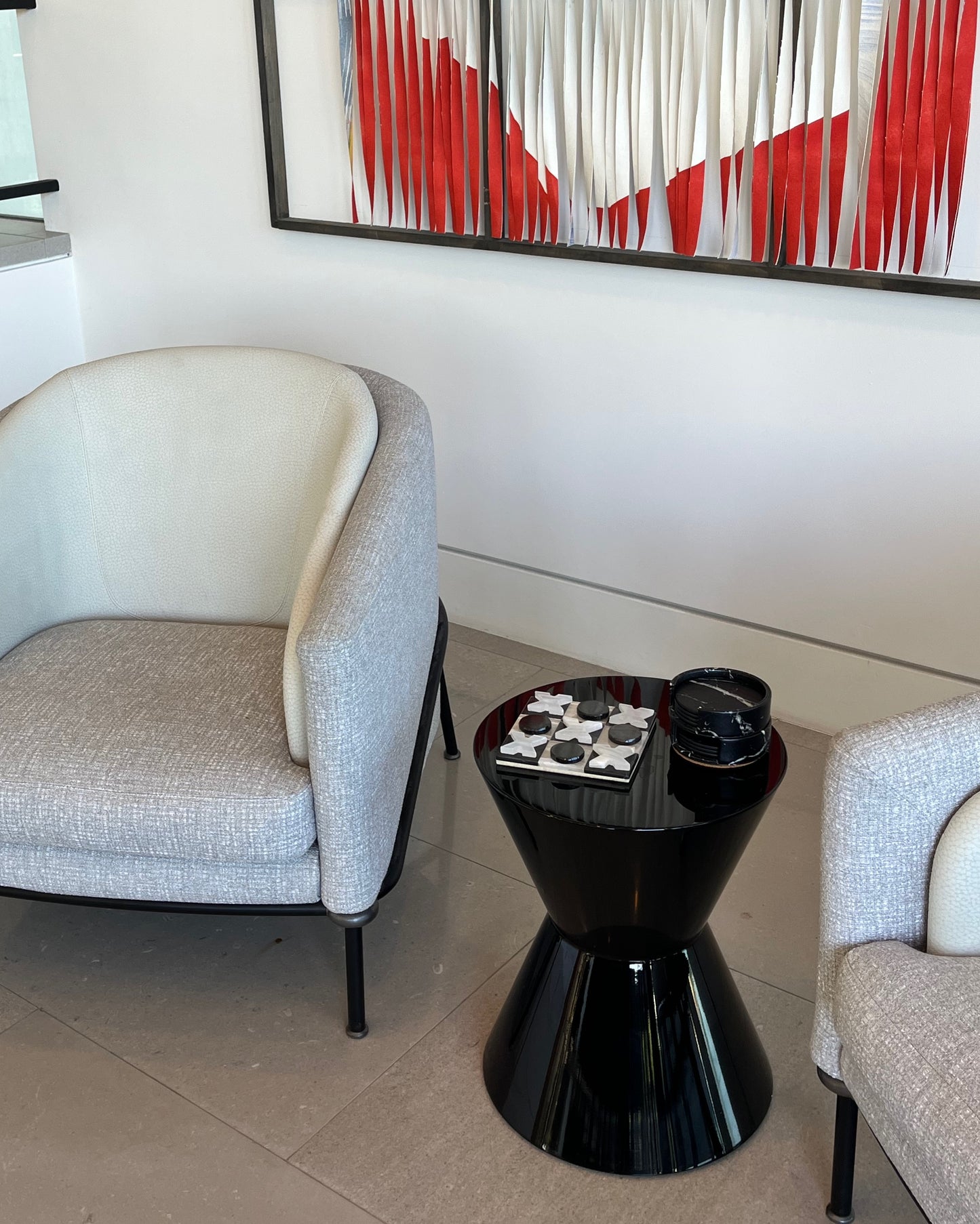 Modern living room with a gray armchair, black side table, and abstract art on the wall.