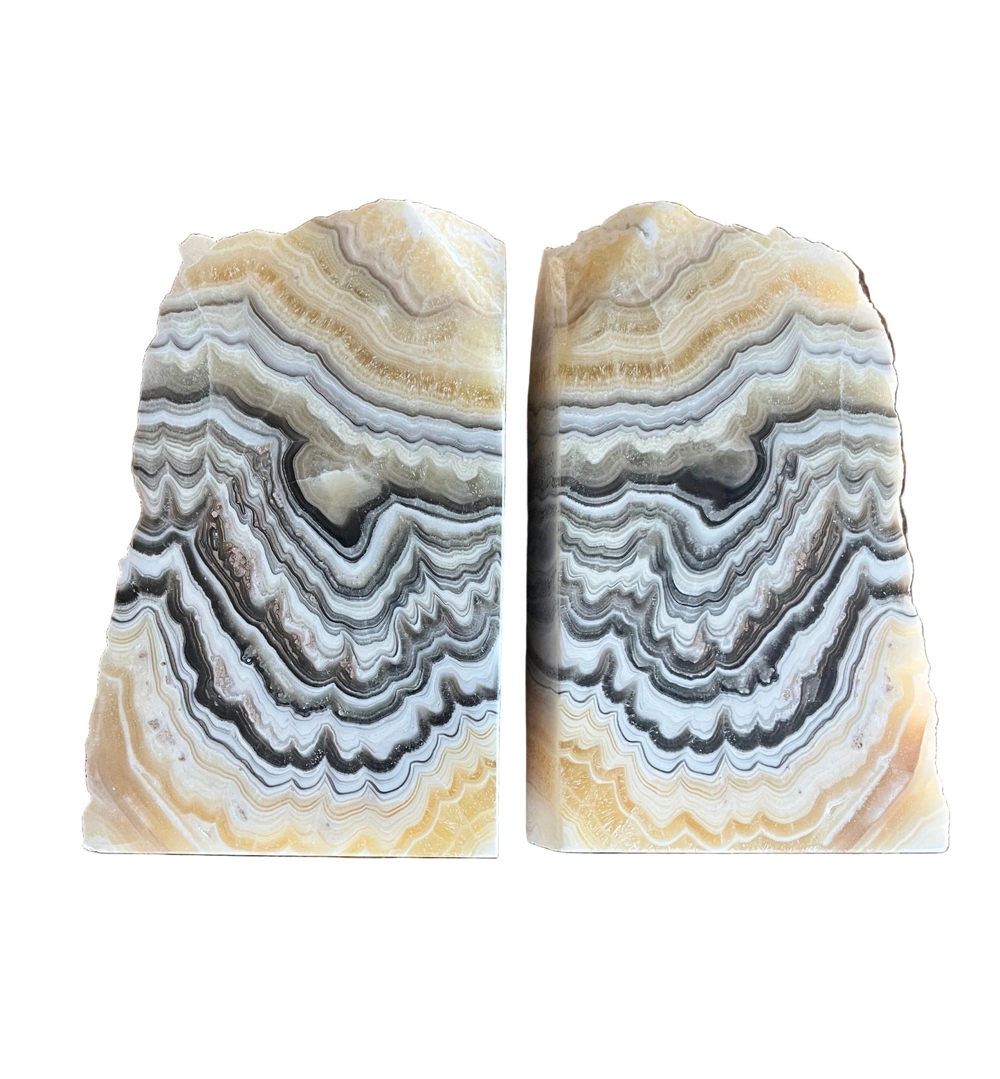 Pair of natural zebra calcite stone bookends with cream, gray, and honey banding on wood surface