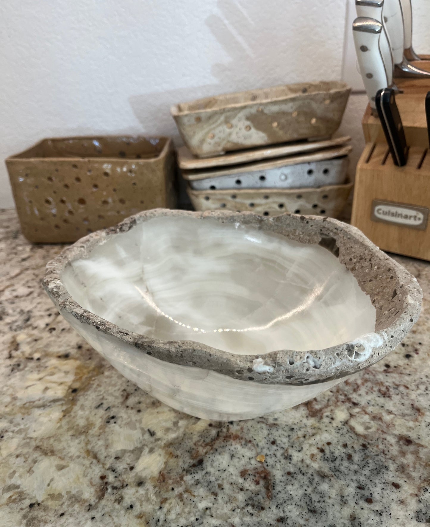 White onyx stone bowl with natural raw edge rim on kitchen counter