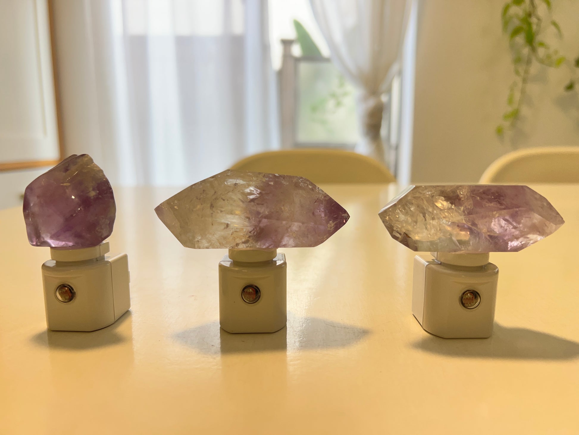 Three crystal amethyst night lights on a table with a blurred background