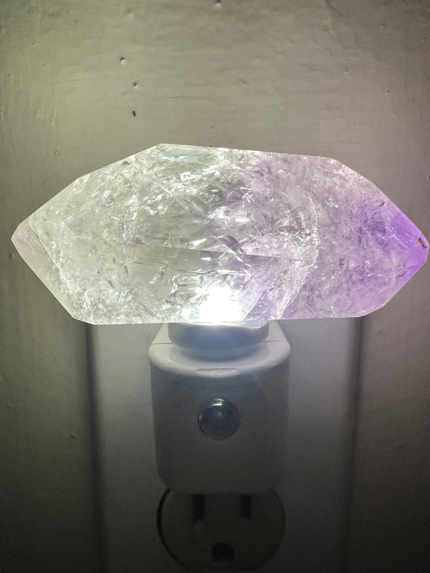 Amethyst crystal night light attached to a wall socket