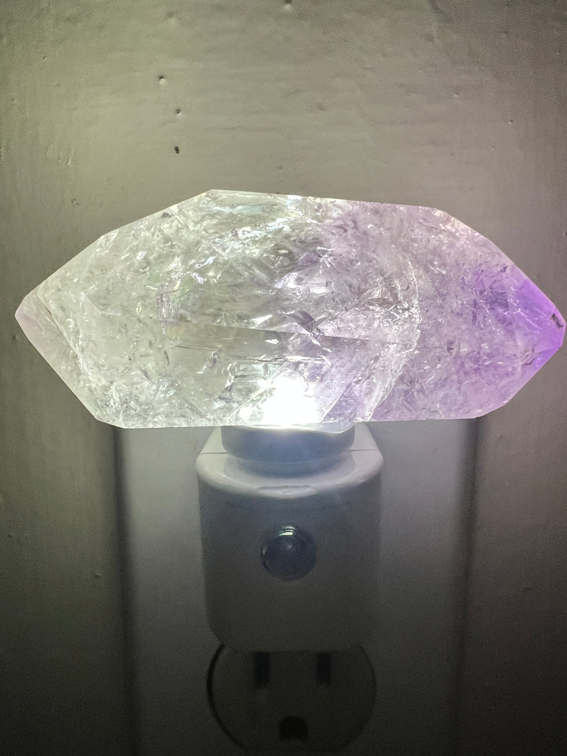 Amethyst crystal night light attached to a wall socket
