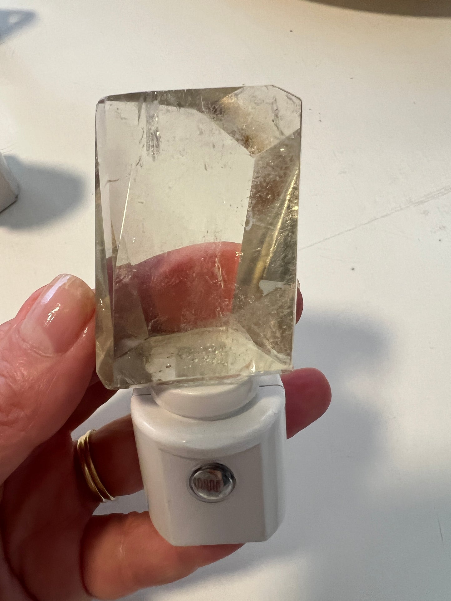 Citrine quartz attached to a white night light base held by a hand on a light background