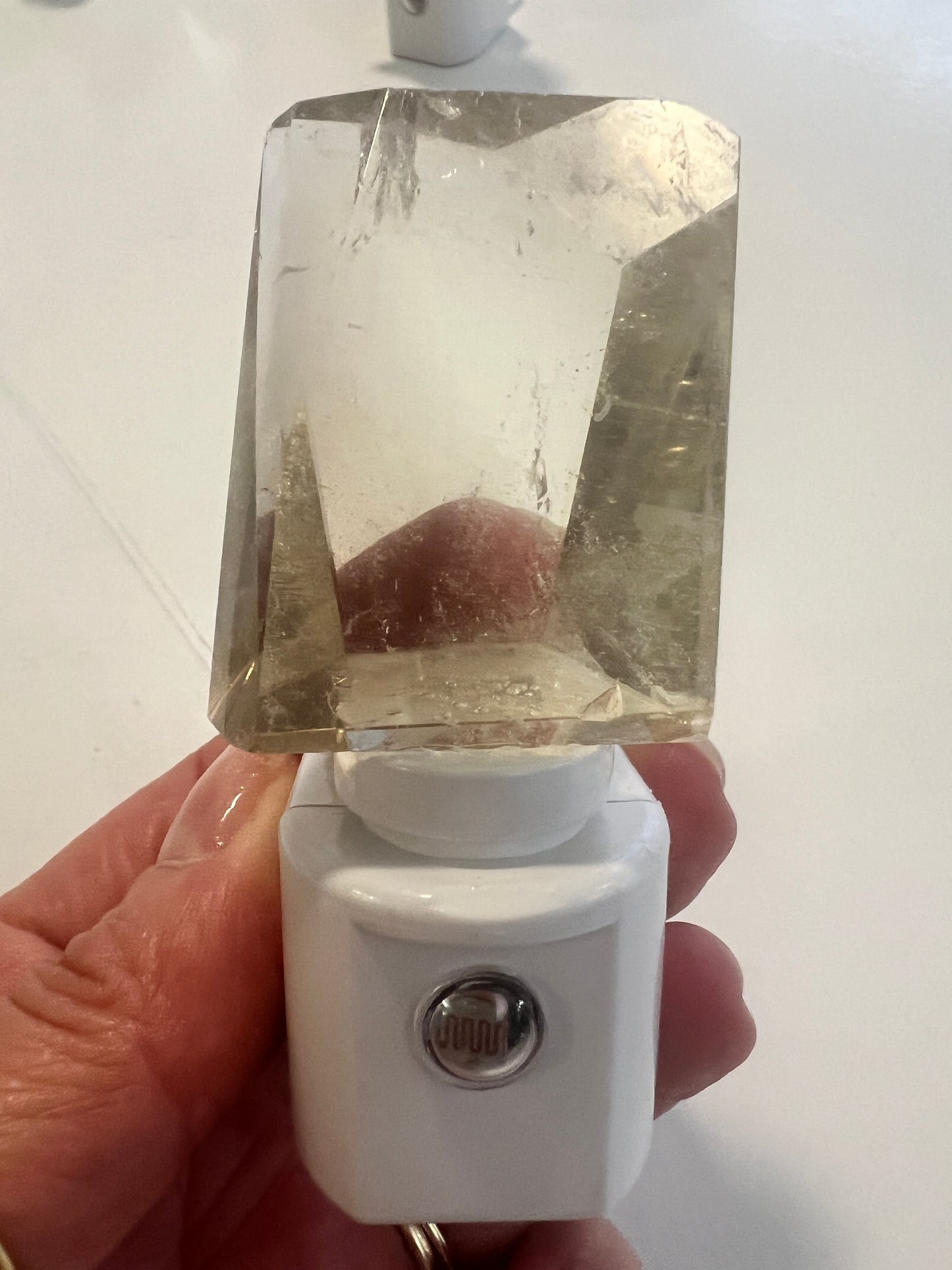 Hand holding a light yellow citrine night light against a light background