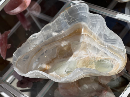 A hand-carved decorative bowl made of white and green onyx, displaying natural crystal patterns and a band of light brown