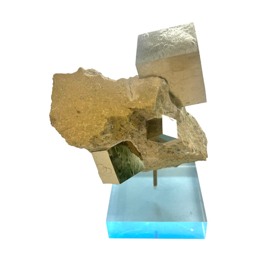 Gold Pyrite cubes in matrix base on a clear blue stand with a white background