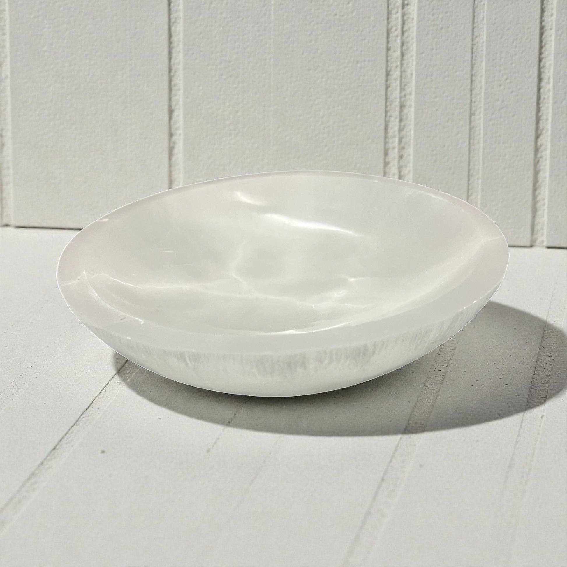 White ceramic bowl on a white wooden surface with a white paneled background