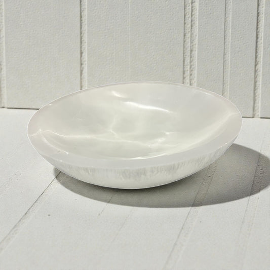 White ceramic bowl on a white wooden surface with a white paneled background