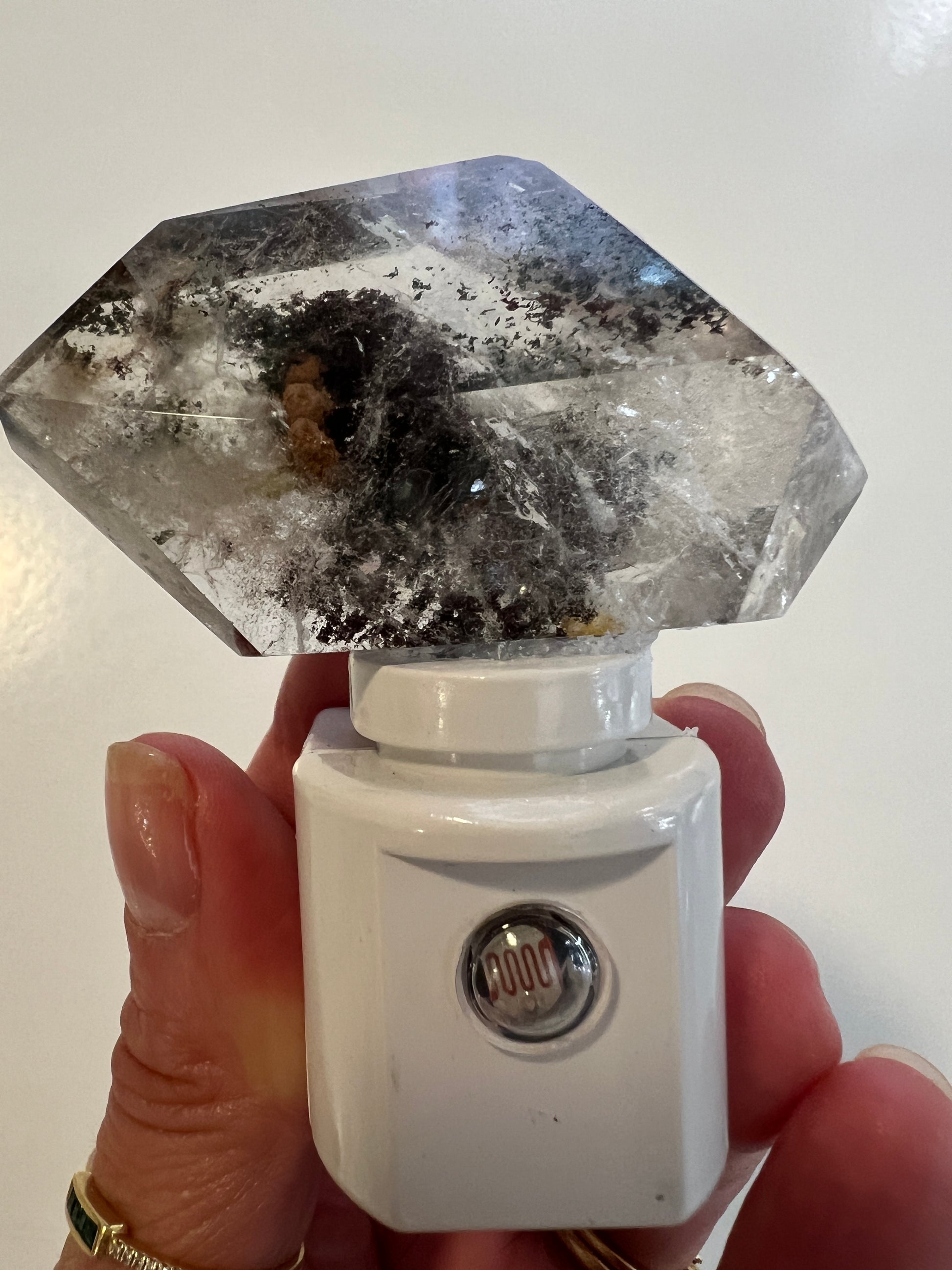 Person holding a crystal night light against a white background