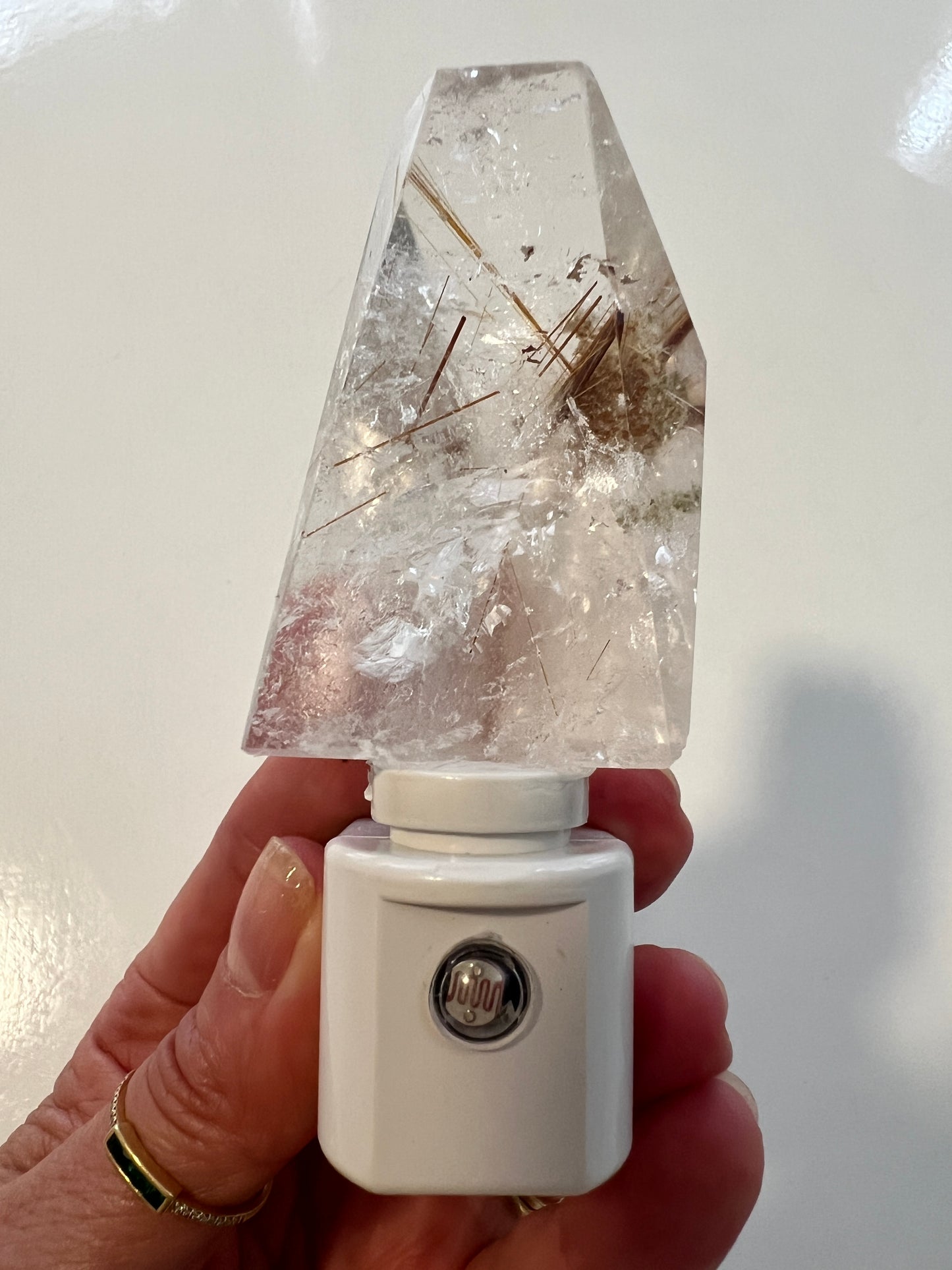 Crystal with a white led base attached, held by a hand on a light background