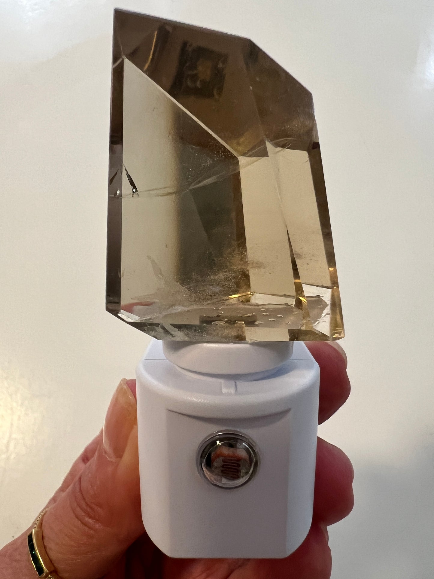 Crystal night light fixture with white base held by a hand on a light background