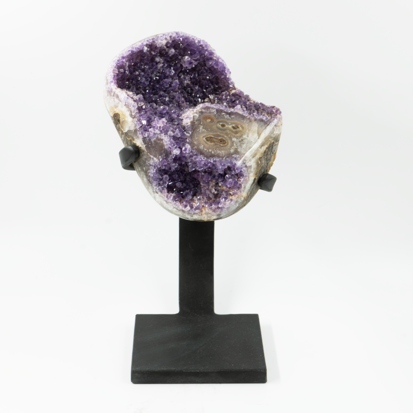 A large amethyst crystal with a stalactite eye on a black stand against a white background.