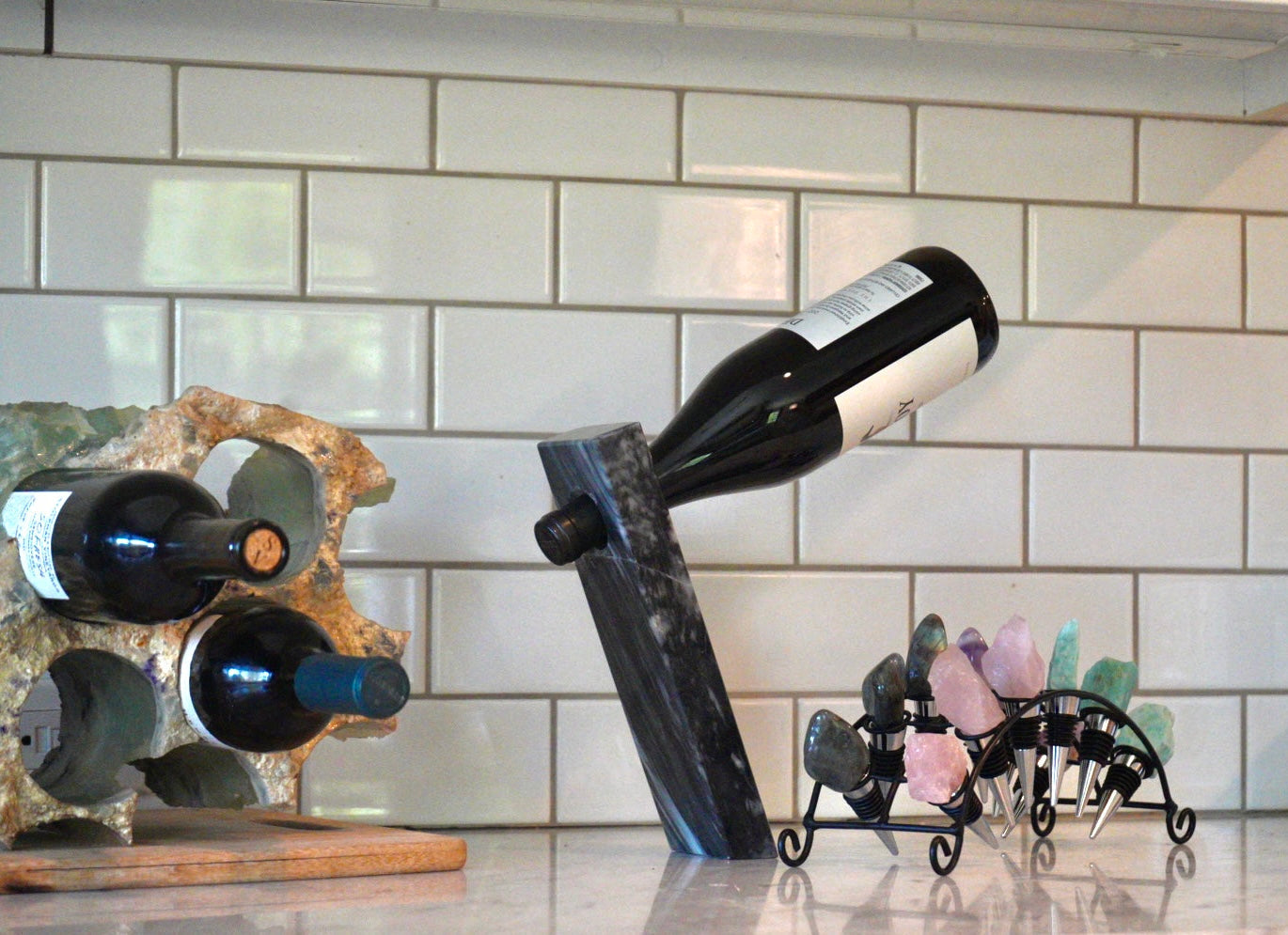 Wine bottles in a fluorite rack and a wine bottle on a stone stand against a tiled wall