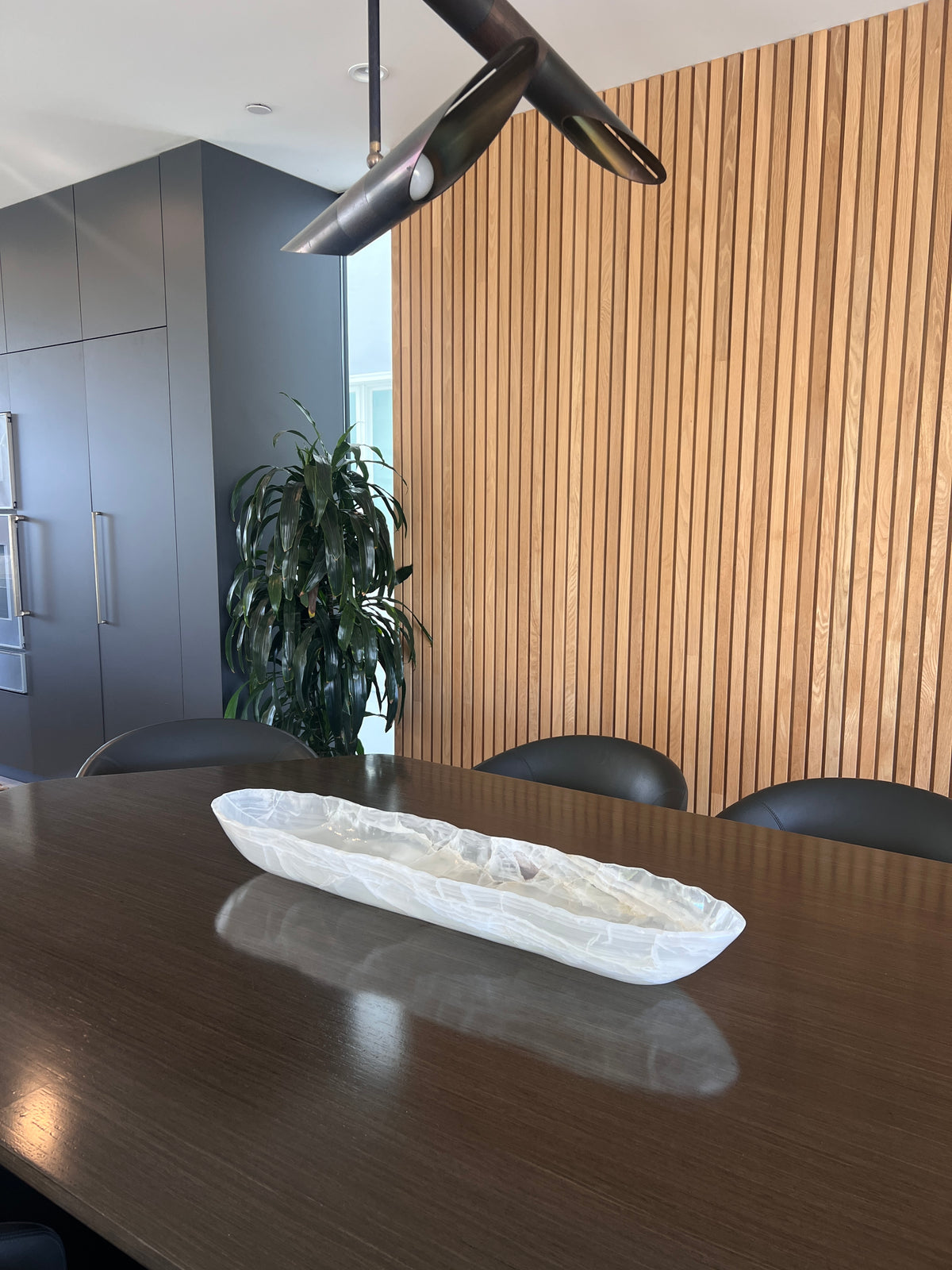 Long white oval bowl on a dark wooden table with a modern interior background