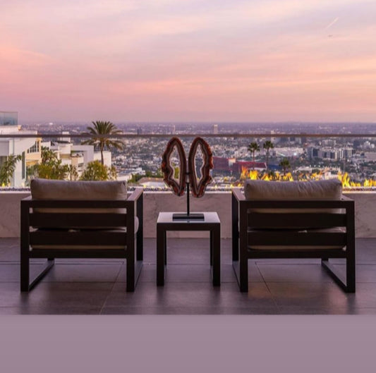 Agate Quartz Butterfly Wings on a balcony overlooking a city at sunset with pink skies