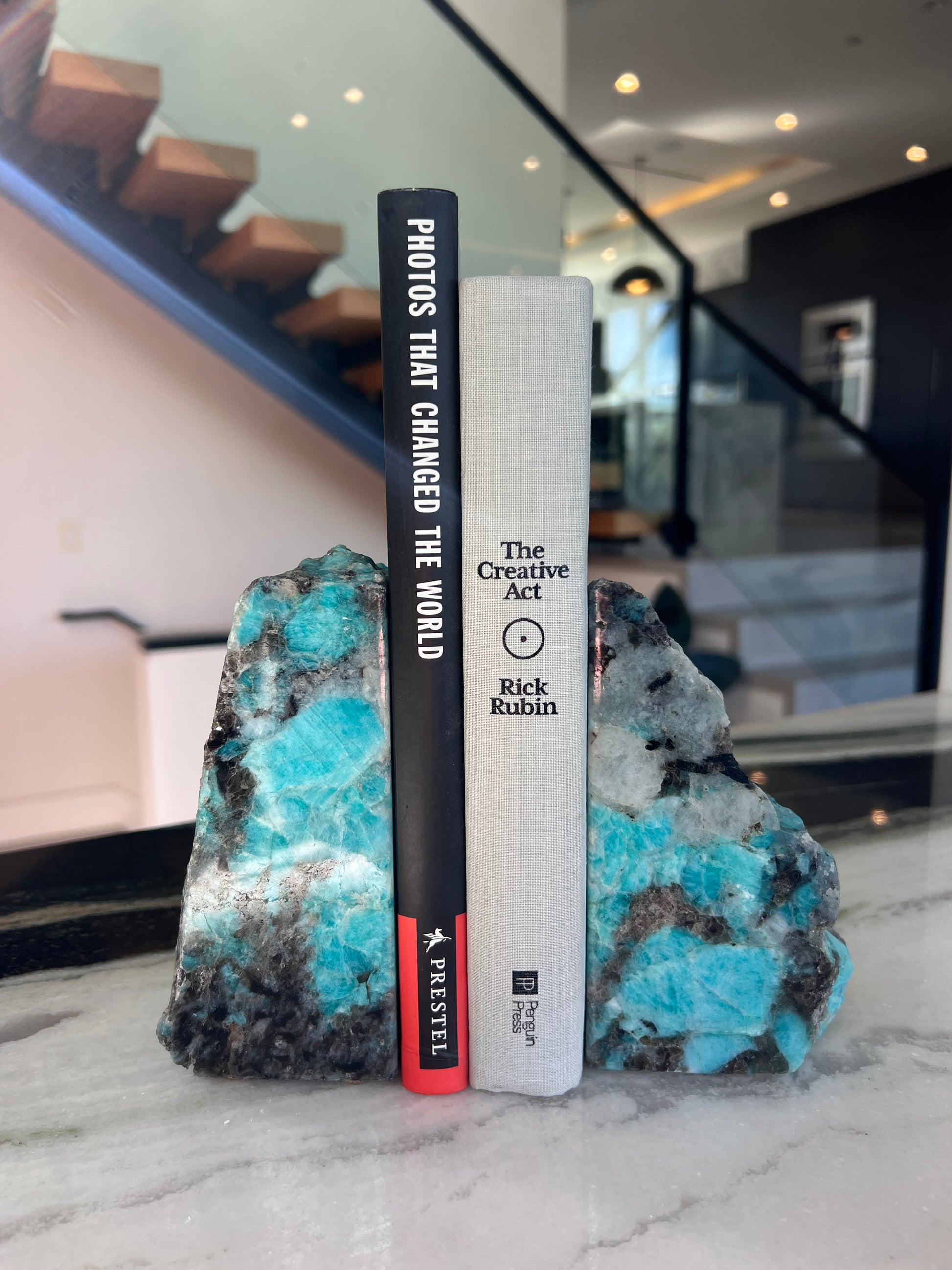 Books on a decorative stone surface held by amazonite bookends with a blurred indoor background.