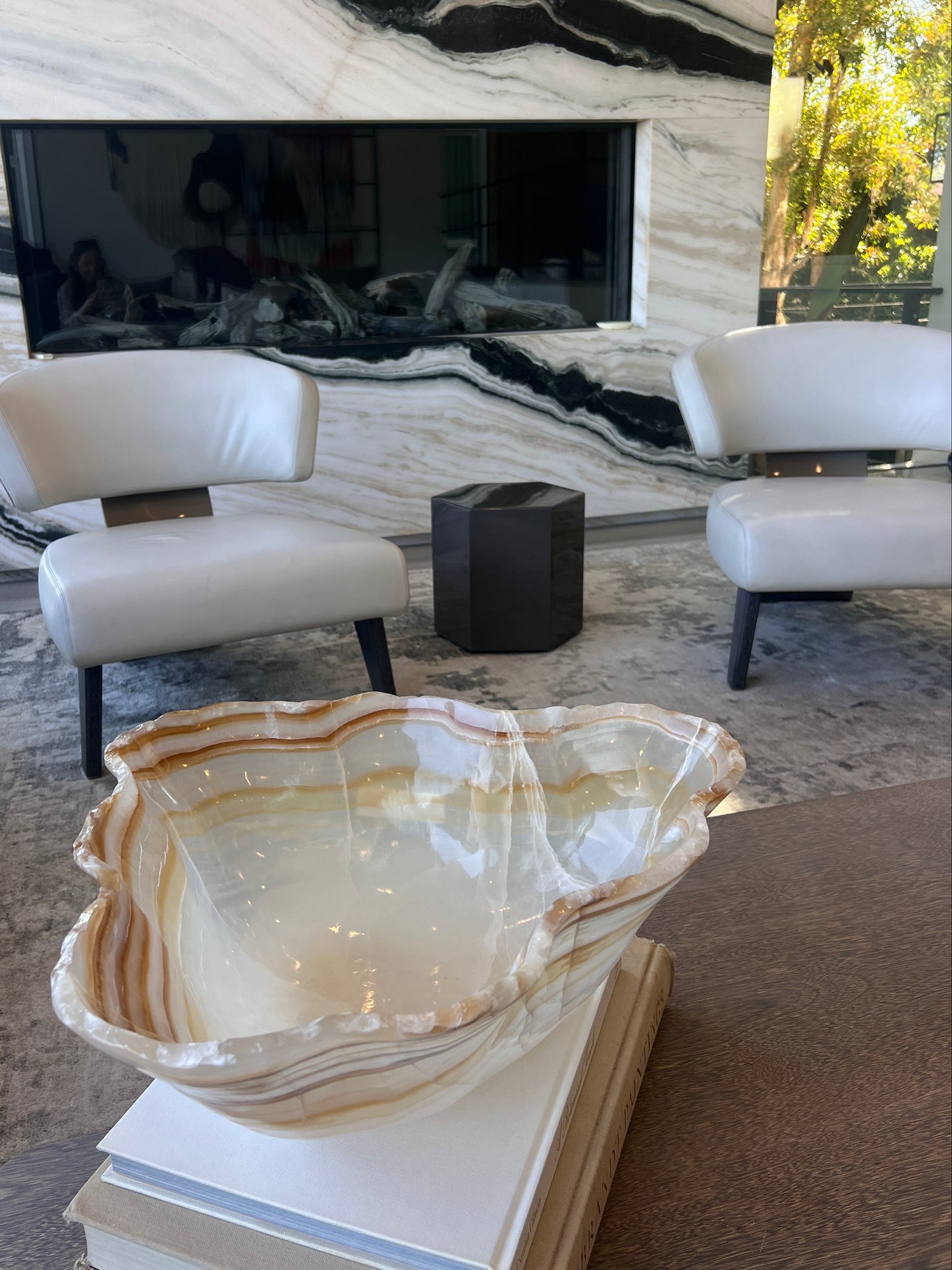 Decorative onyx bowl in a modern living room with marble wall and furniture.