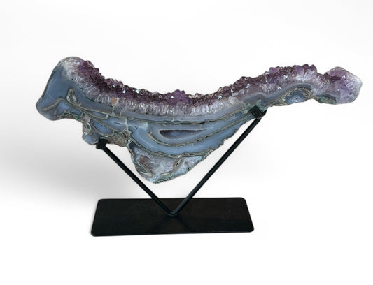 An Amethyst Agate Druzy wave on a black stand, displaying layered patterns of purple and blue with a crystalline structure.