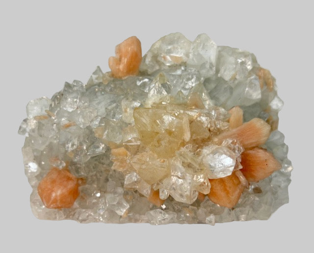 Mineral sample with clear and orange crystals on a white background