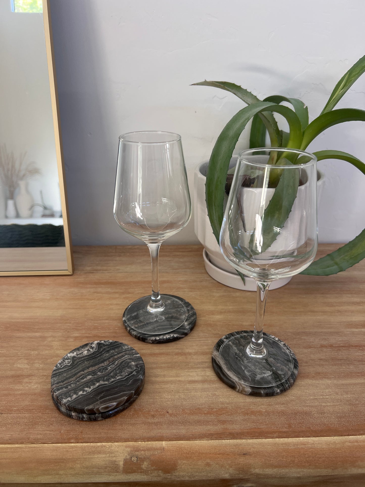 Two wine glasses on a wooden surface with three coasters.