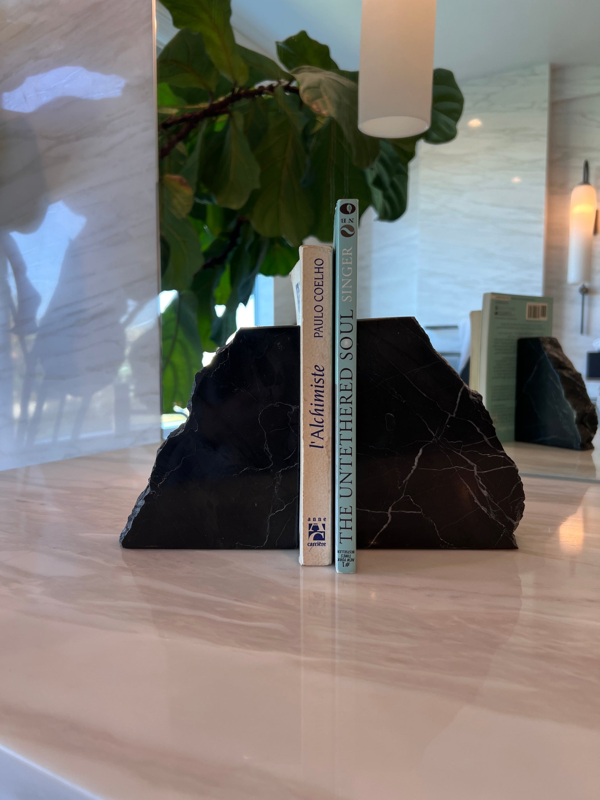 Black bookends with two books on a wooden surface with decorative elements in the background