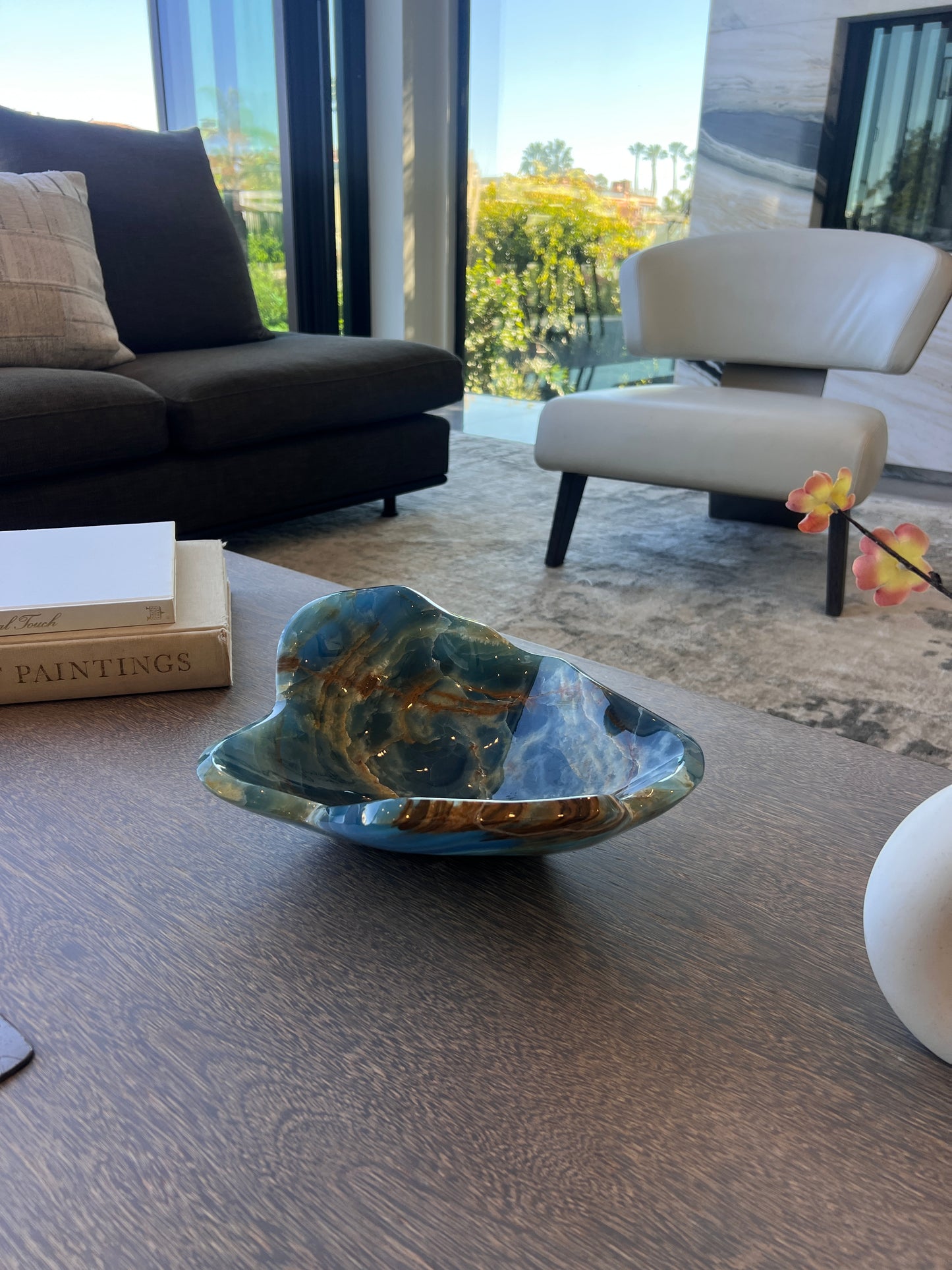 Decorative blue onyx bowl on a table with a modern living room in the background