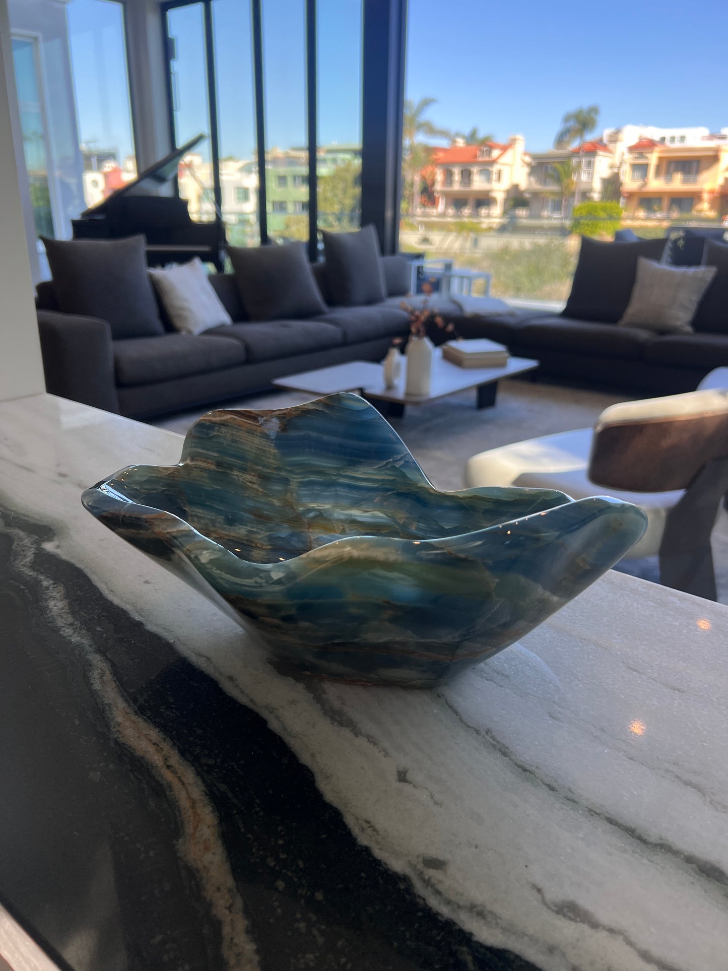 Marble-patterned blue onyx bowl on a marble surface with a living room in the background