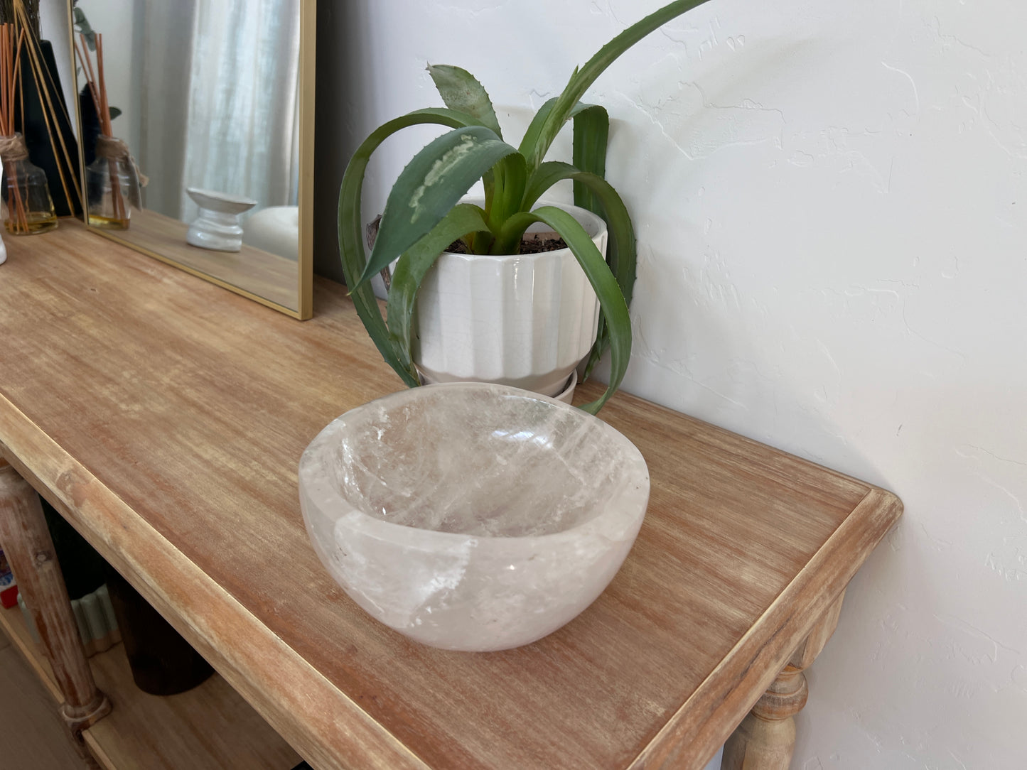 Decorative bowl on a wooden table with a plant in the background