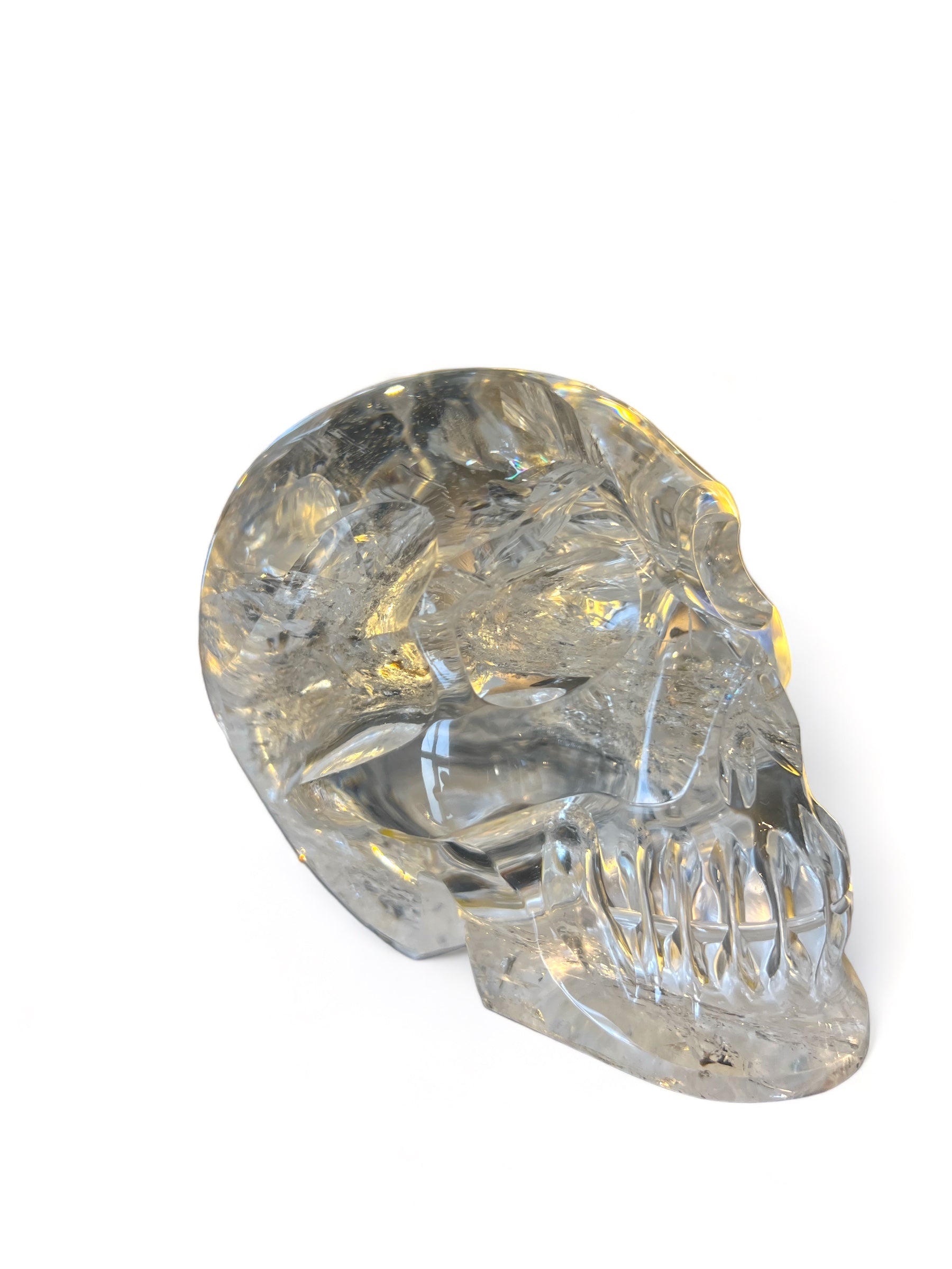 A hand-carved clear quartz skull with a rainbow sheen, commonly associated with spiritual protection and wisdom in various cultures.