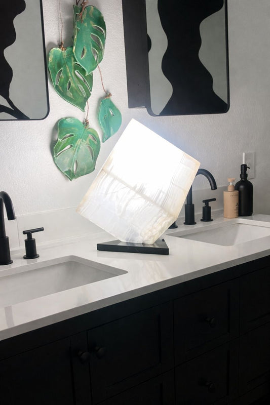 White onyx cube lamp illuminated on modern vanity, glowing stone accent light, sculptural 10 inch cube table lamp
