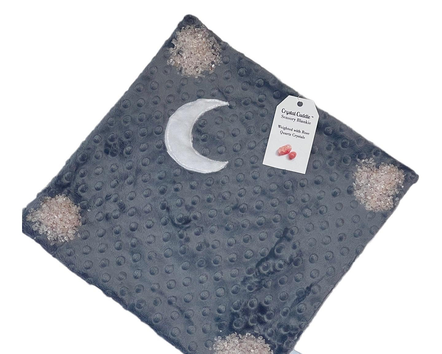 Textured dark grey blanket with moon design and tag and pink crystals showing in each corner on a white background