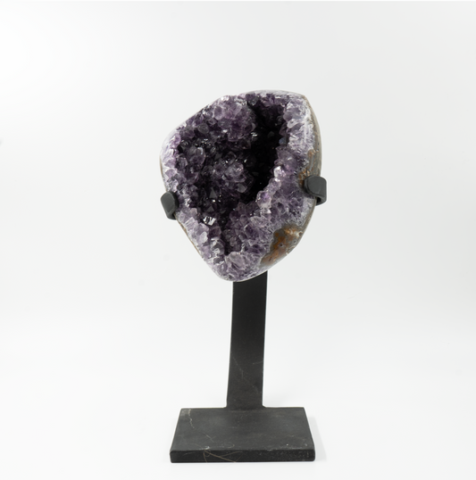 A large amethyst crystal on a black stand, displaying its deep purple color and rough texture.