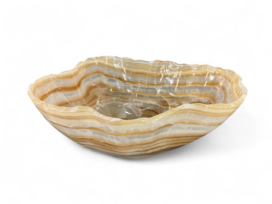 A hand-carved decorative bowl made of amber banded onyx, displaying natural swirling bands of color.