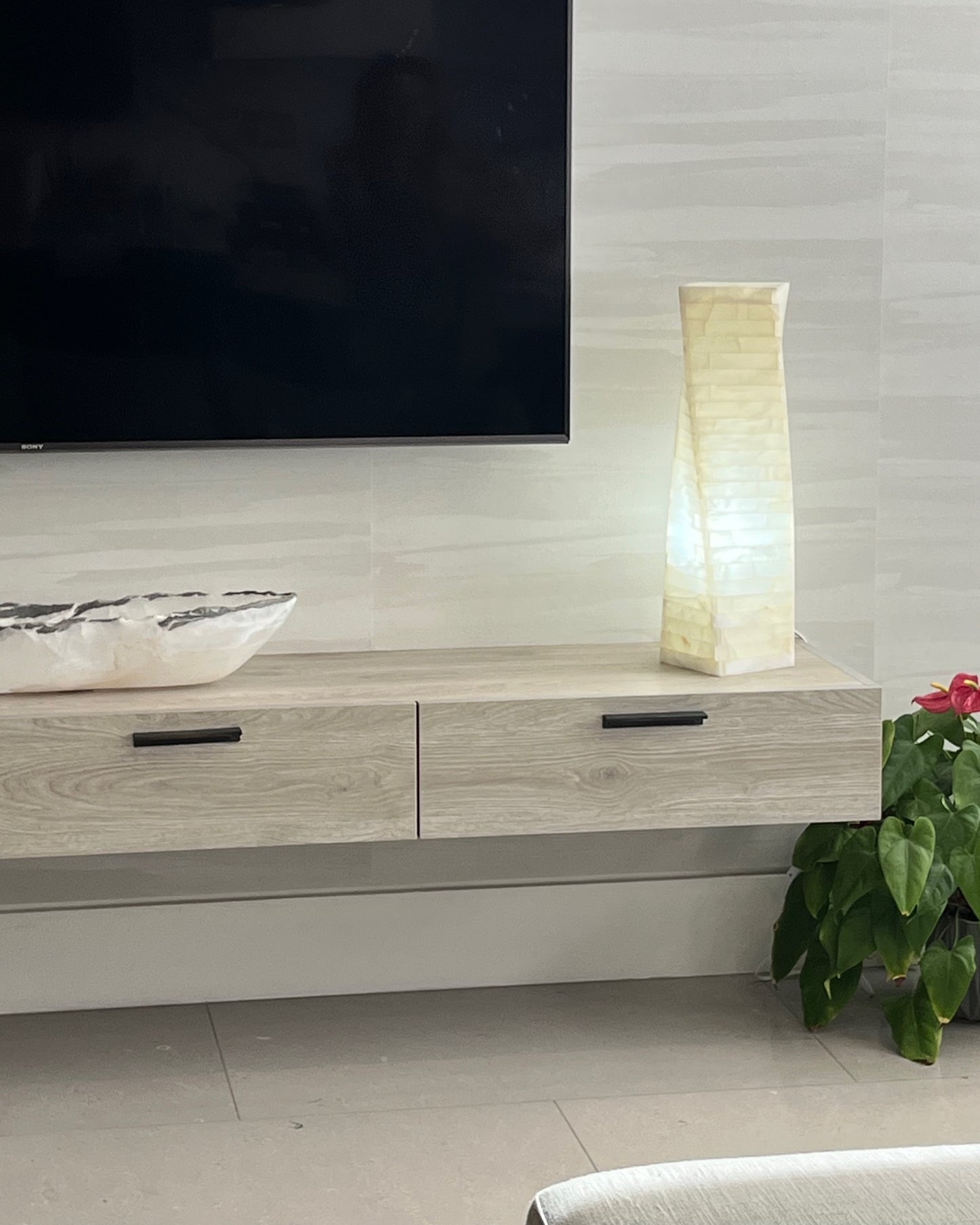 Modern living room with a TV mounted on the wall, wooden cabinet, and decorative items.