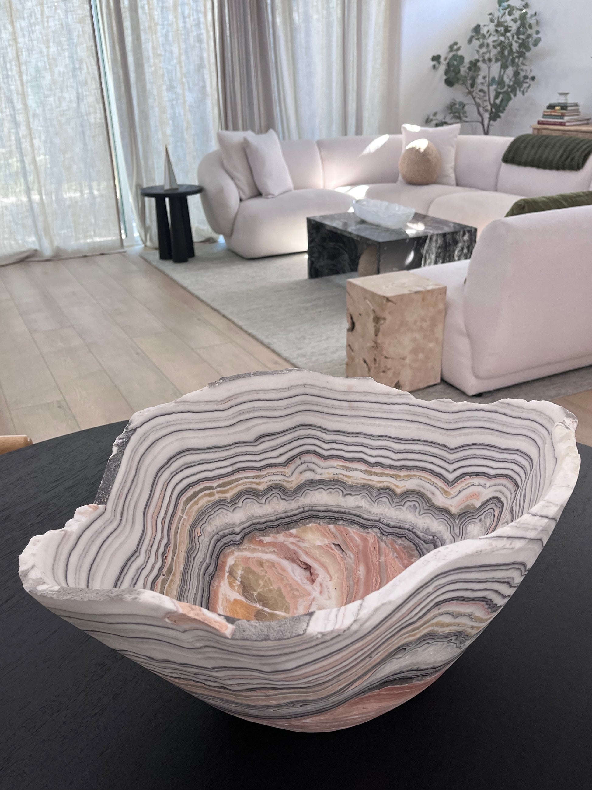 Decorative agate bowl on a dark surface with a modern living room in the background
