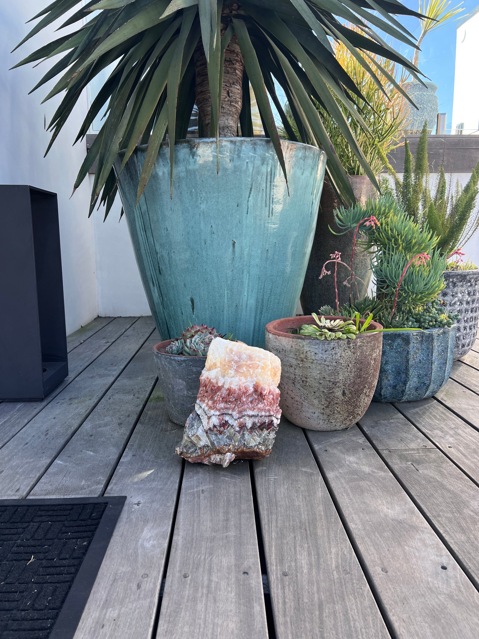 Decorative arrangement of potted plants and a large decorative crystal on a wooden deck.