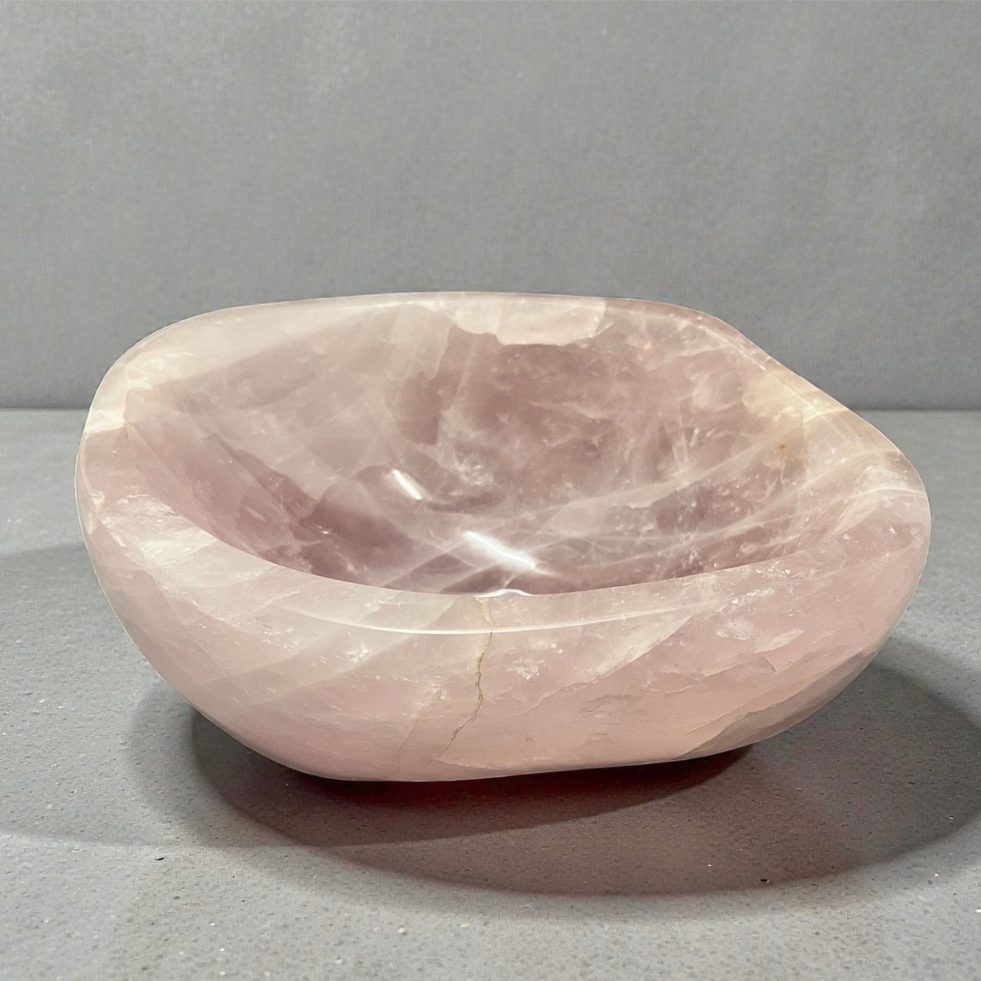Rose quartz stone bowl on a gray background