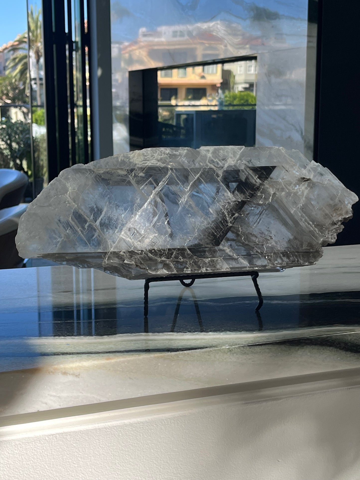 Large crystal Selenite on a stand with a reflective surface background