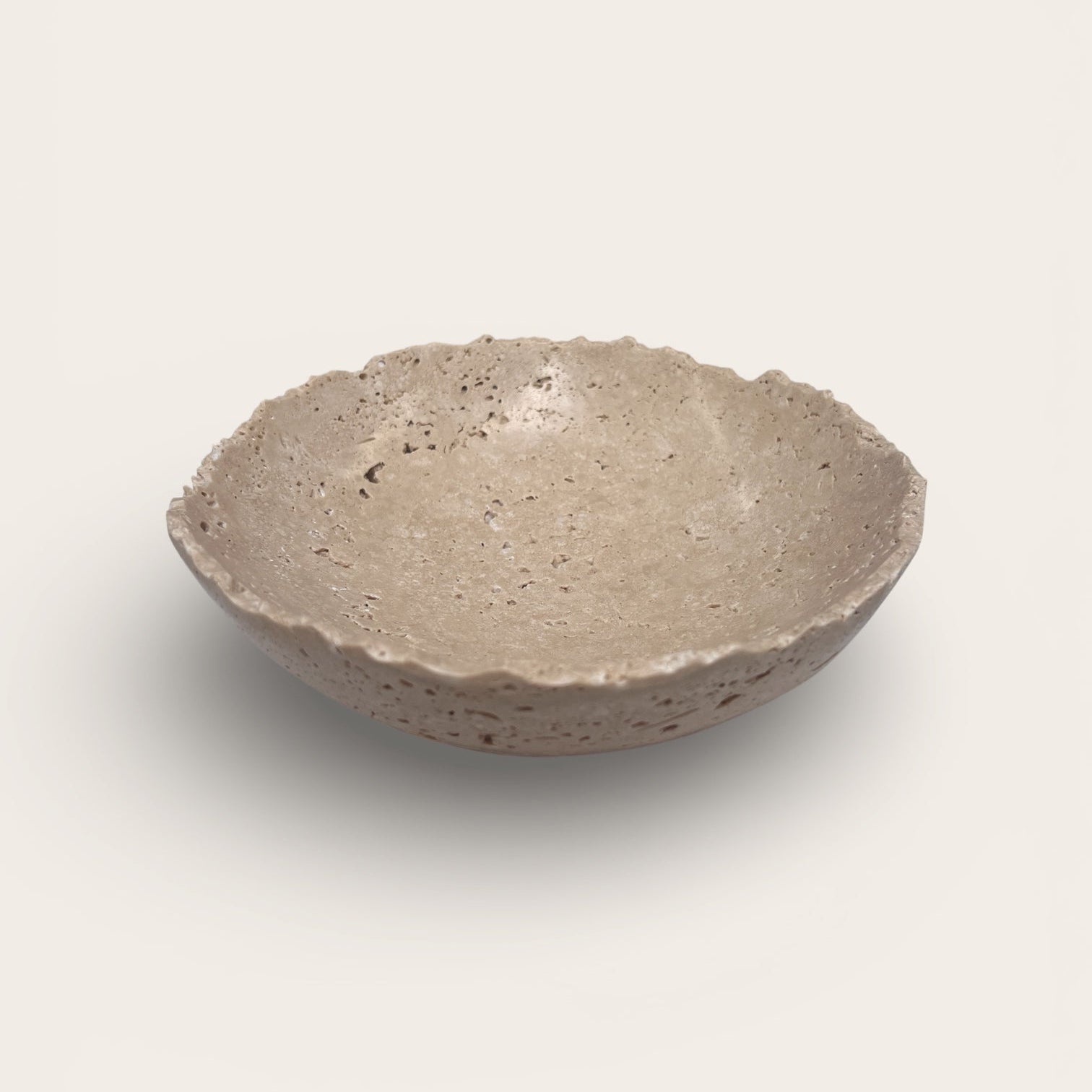 Hand-carved travertine stone bowl with natural pitting and shallow sculptural form