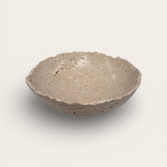 Hand-carved travertine stone bowl with natural pitting and shallow sculptural form